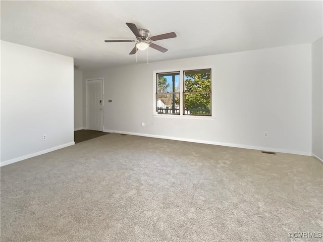 carpeted empty room with visible vents, a ceiling fan, and baseboards