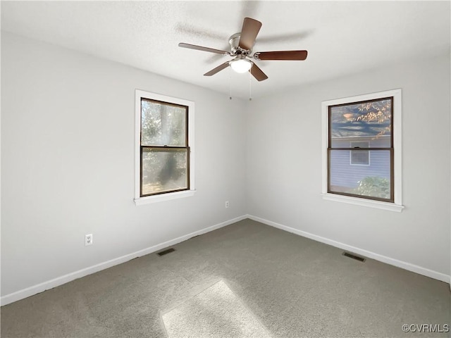 carpeted empty room featuring baseboards, visible vents, and ceiling fan