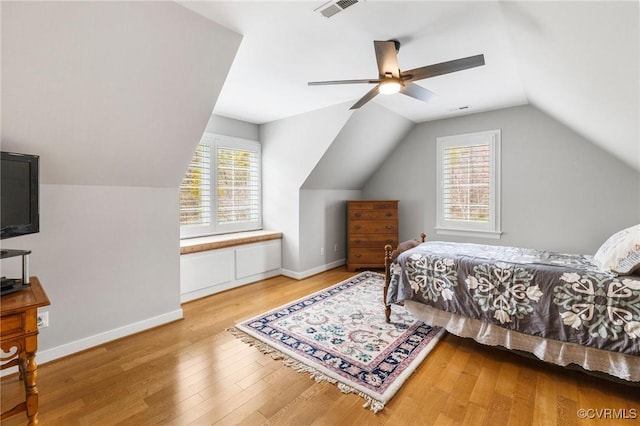 bedroom featuring vaulted ceiling, visible vents, baseboards, and wood finished floors