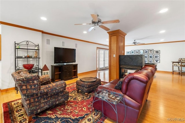 living room with wood finished floors, baseboards, and ornamental molding