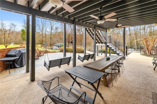 view of patio with outdoor dry bar, stairs, a ceiling fan, and fence