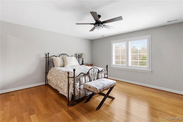 bedroom featuring ceiling fan, light wood-style floors, visible vents, and baseboards