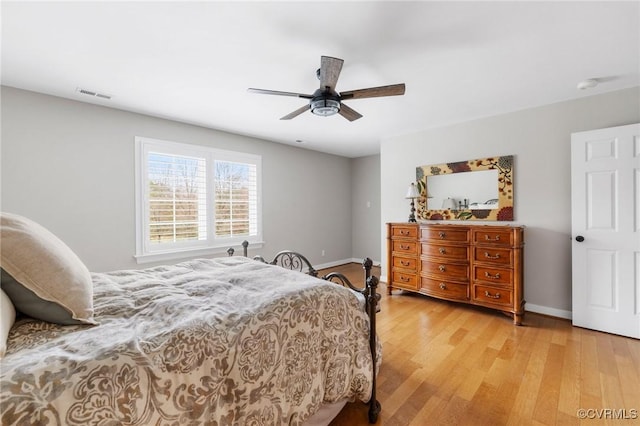 bedroom featuring ceiling fan, visible vents, baseboards, and light wood-style flooring