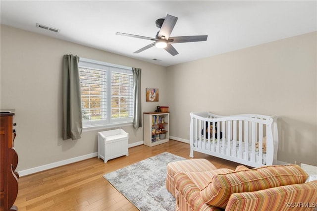 bedroom with ceiling fan, visible vents, baseboards, and wood finished floors