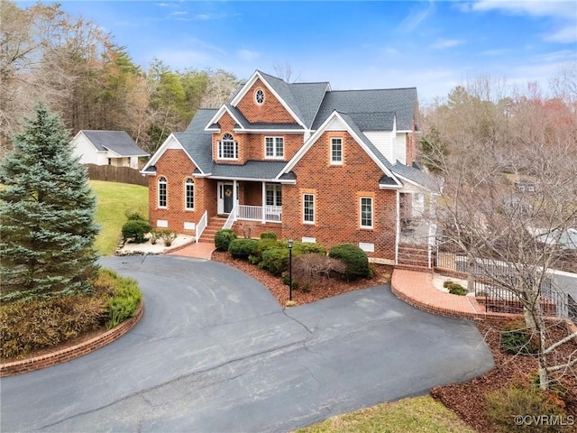 view of front of home with crawl space, aphalt driveway, brick siding, and fence