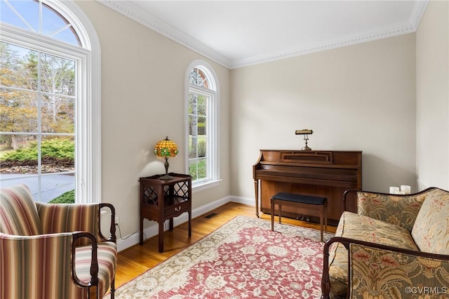 sitting room with crown molding, light wood-style floors, and baseboards