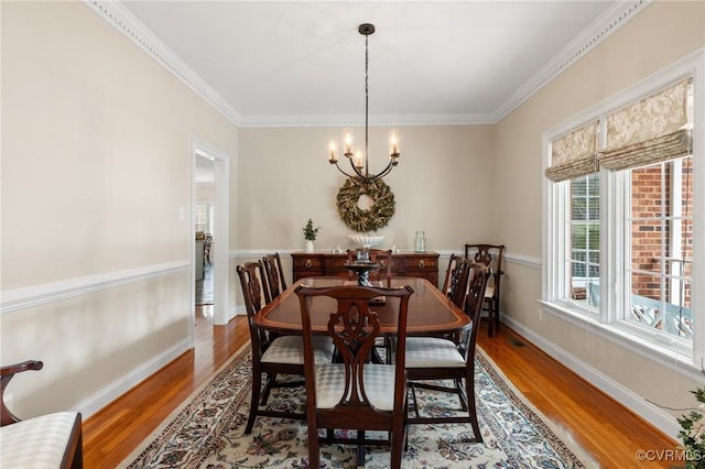 dining area featuring baseboards, a notable chandelier, wood finished floors, and crown molding