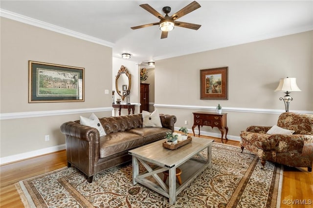 living area with ceiling fan, wood finished floors, baseboards, and ornamental molding