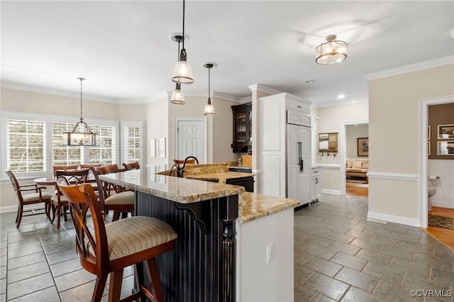 kitchen featuring crown molding, a kitchen breakfast bar, light stone counters, and baseboards