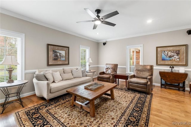 living room featuring ceiling fan, light wood-style flooring, baseboards, and ornamental molding