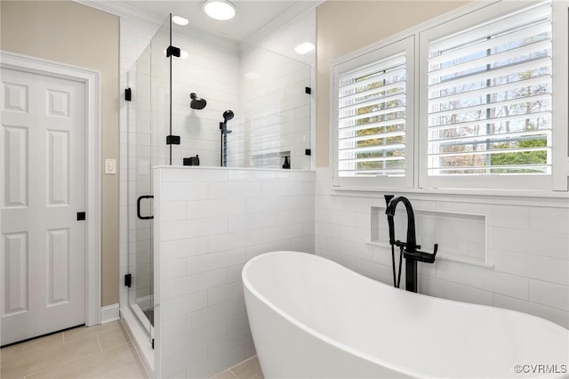 full bath with a freestanding tub, a stall shower, tile patterned flooring, crown molding, and tile walls