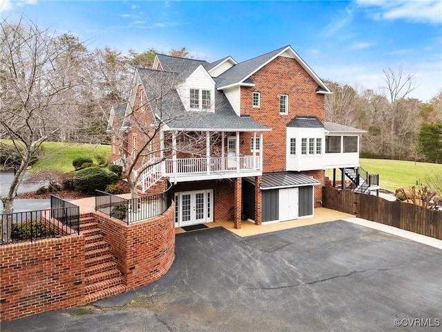 view of front of house with french doors, an outdoor structure, a sunroom, brick siding, and stairs