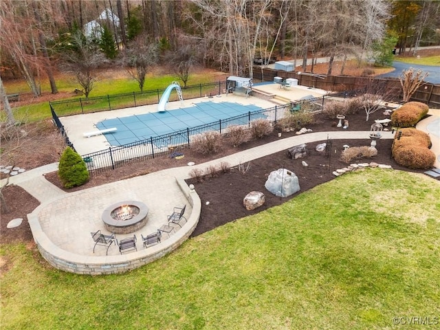 view of pool with fence, a water slide, an outdoor fire pit, a yard, and a patio area