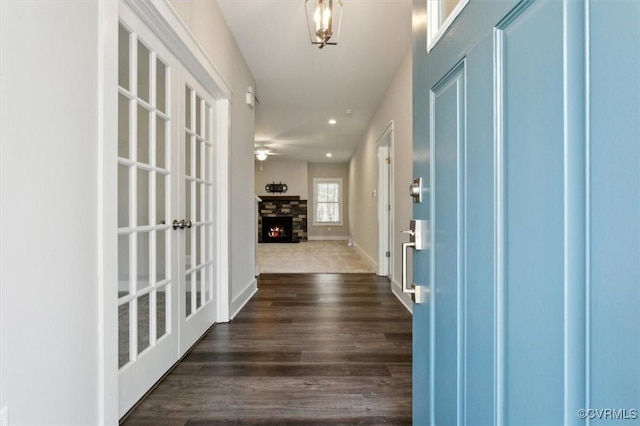 entrance foyer featuring baseboards, dark wood finished floors, recessed lighting, a stone fireplace, and french doors