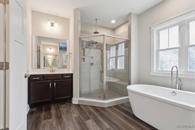 full bathroom featuring wood finished floors, a soaking tub, a stall shower, and vanity