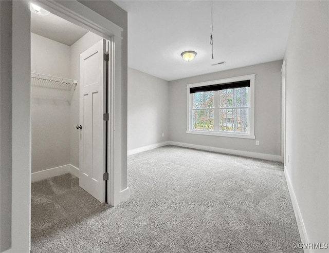 carpeted spare room featuring visible vents, attic access, and baseboards