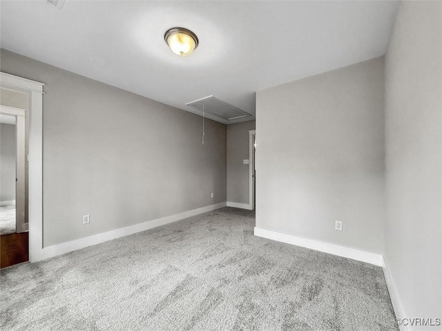 carpeted empty room with baseboards and attic access