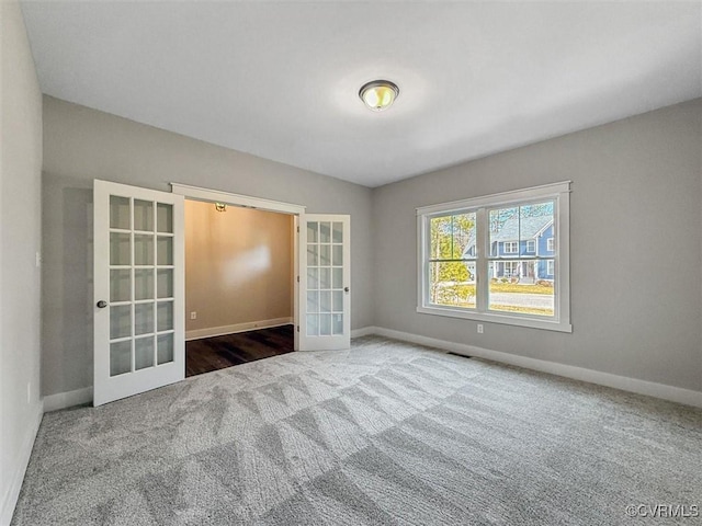 unfurnished room with carpet, visible vents, french doors, and baseboards