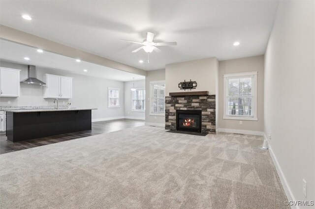 living area featuring a stone fireplace, carpet, and baseboards