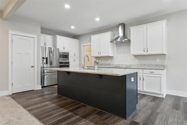 kitchen featuring a sink, stainless steel appliances, white cabinetry, and wall chimney range hood