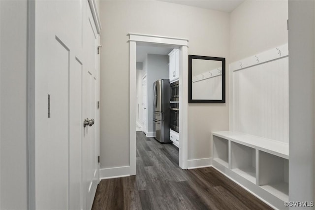 hall featuring dark wood-type flooring and baseboards