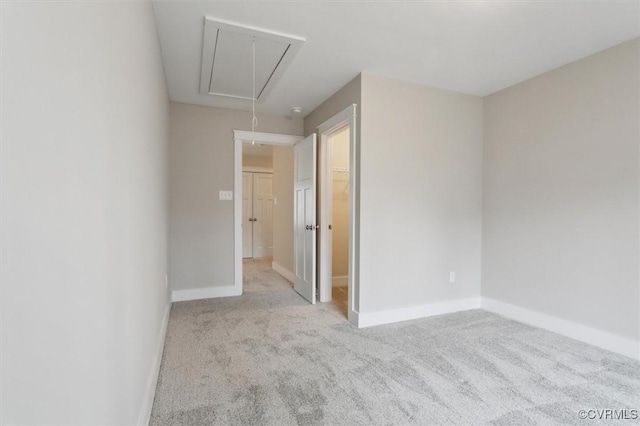 unfurnished bedroom with baseboards, attic access, a closet, a walk in closet, and carpet flooring