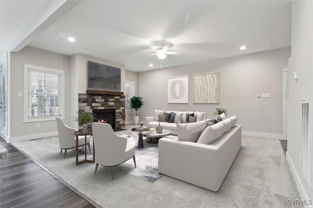 living area featuring recessed lighting, baseboards, and a stone fireplace