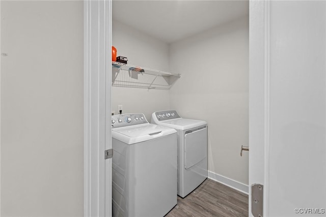 clothes washing area featuring laundry area, independent washer and dryer, baseboards, and wood finished floors