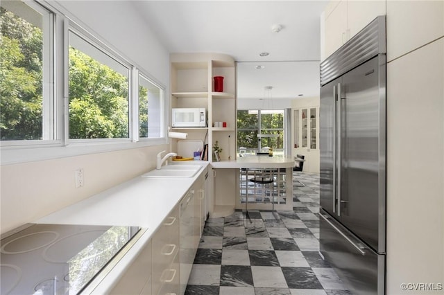 kitchen with stainless steel built in fridge, modern cabinets, a sink, electric stovetop, and white microwave