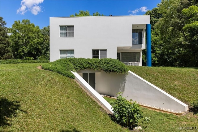 back of house featuring stucco siding and a yard