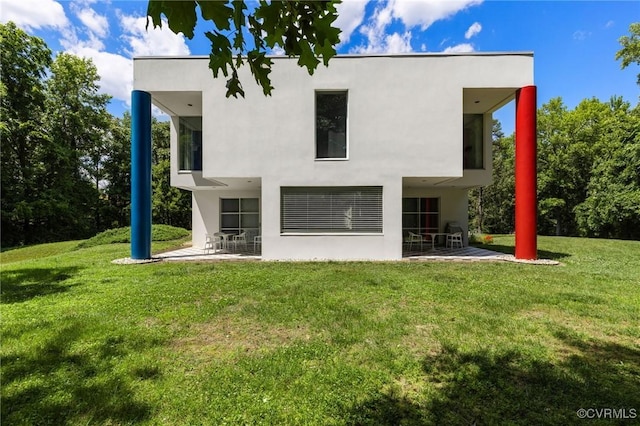 rear view of property featuring stucco siding, a patio, and a lawn