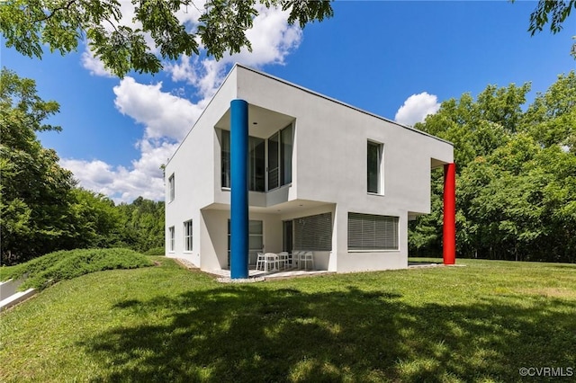 back of property with stucco siding, a yard, and a patio area