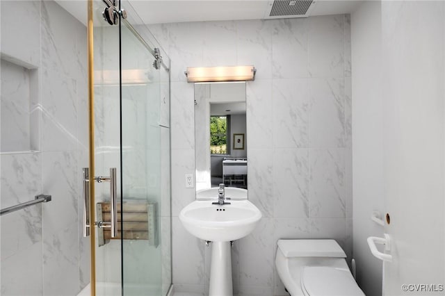 bathroom featuring a marble finish shower, visible vents, toilet, and tile walls