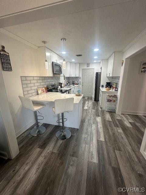 kitchen with stainless steel appliances, a peninsula, dark wood-style flooring, and crown molding