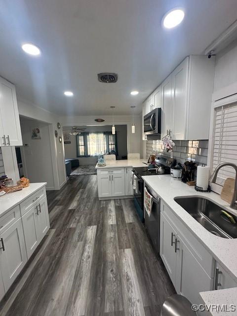 kitchen with stainless steel microwave, dishwasher, electric range oven, a peninsula, and a sink