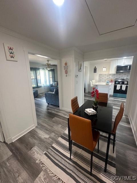 dining space featuring baseboards, a ceiling fan, dark wood finished floors, and crown molding