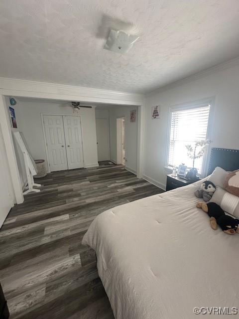 bedroom with a closet, a textured ceiling, ornamental molding, and dark wood-style flooring