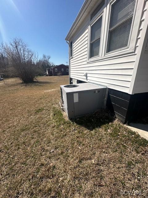 view of home's exterior featuring a lawn and central AC