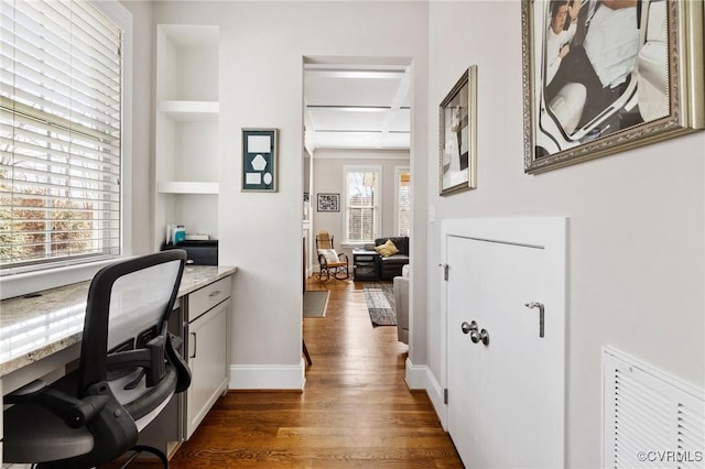 home office featuring dark wood-style floors, visible vents, built in shelves, and baseboards