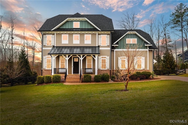 craftsman-style home with brick siding, covered porch, board and batten siding, and a yard