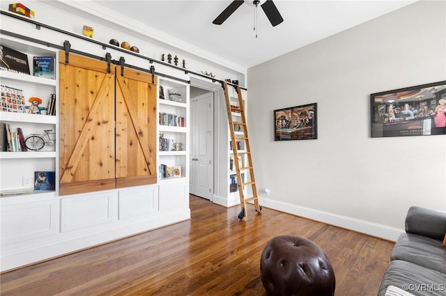 living area featuring a barn door, wood finished floors, baseboards, and ceiling fan