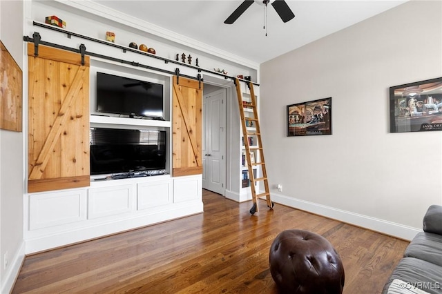 living area with a barn door, baseboards, wood finished floors, and a ceiling fan