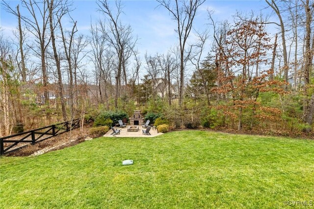 view of yard featuring a patio, an outdoor stone fireplace, and fence