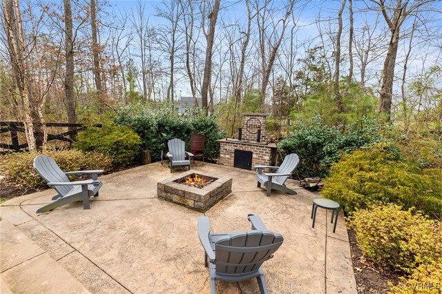 view of patio / terrace featuring a fire pit and an outdoor brick fireplace