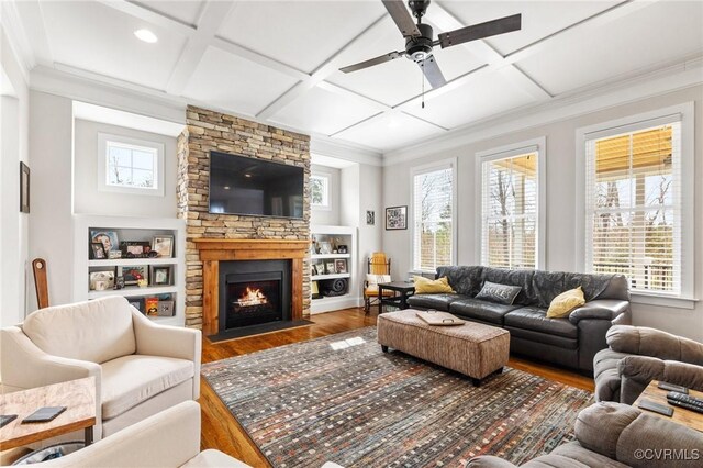 living room with plenty of natural light, coffered ceiling, a stone fireplace, and wood finished floors