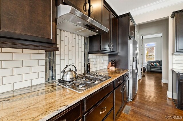 kitchen featuring ornamental molding, under cabinet range hood, tasteful backsplash, appliances with stainless steel finishes, and dark brown cabinets