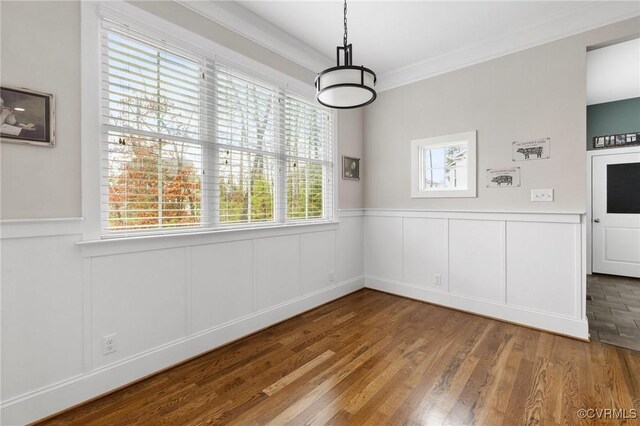 unfurnished dining area featuring wood finished floors, a wainscoted wall, and ornamental molding