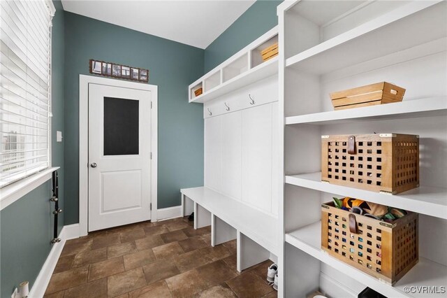 mudroom featuring stone finish floor and baseboards