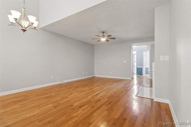 spare room with baseboards, light wood-style floors, and ceiling fan with notable chandelier