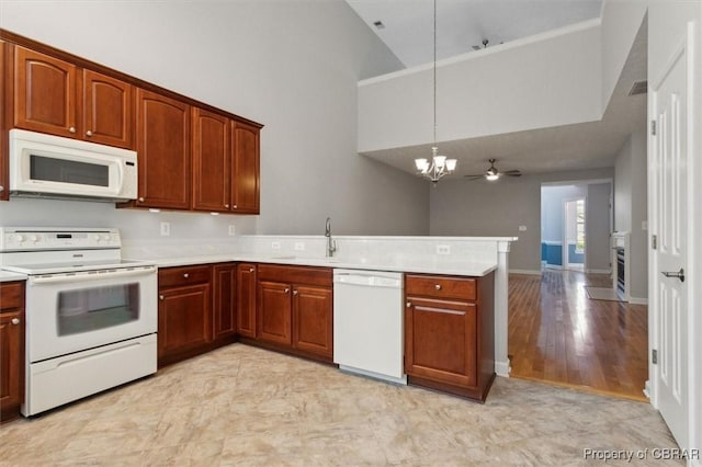 kitchen featuring white appliances, a peninsula, a sink, light countertops, and pendant lighting